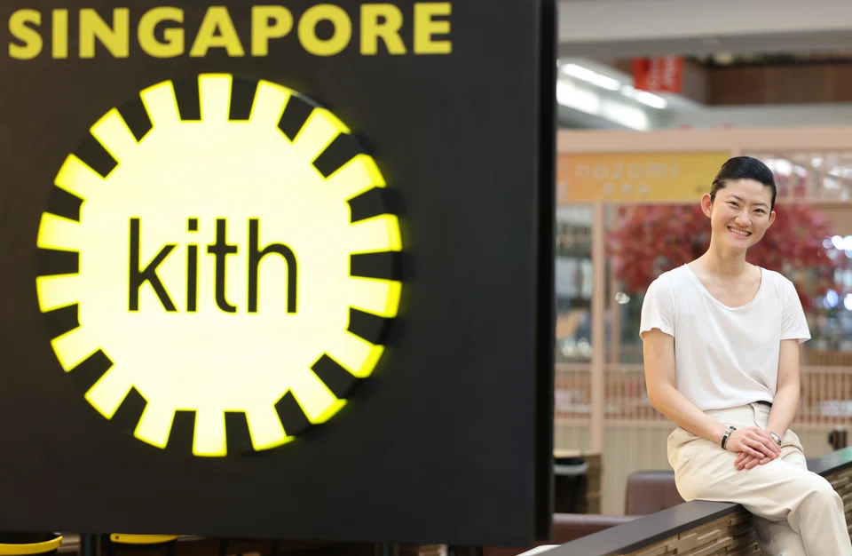 Jane Hia seated beside the Kith Cafe sign